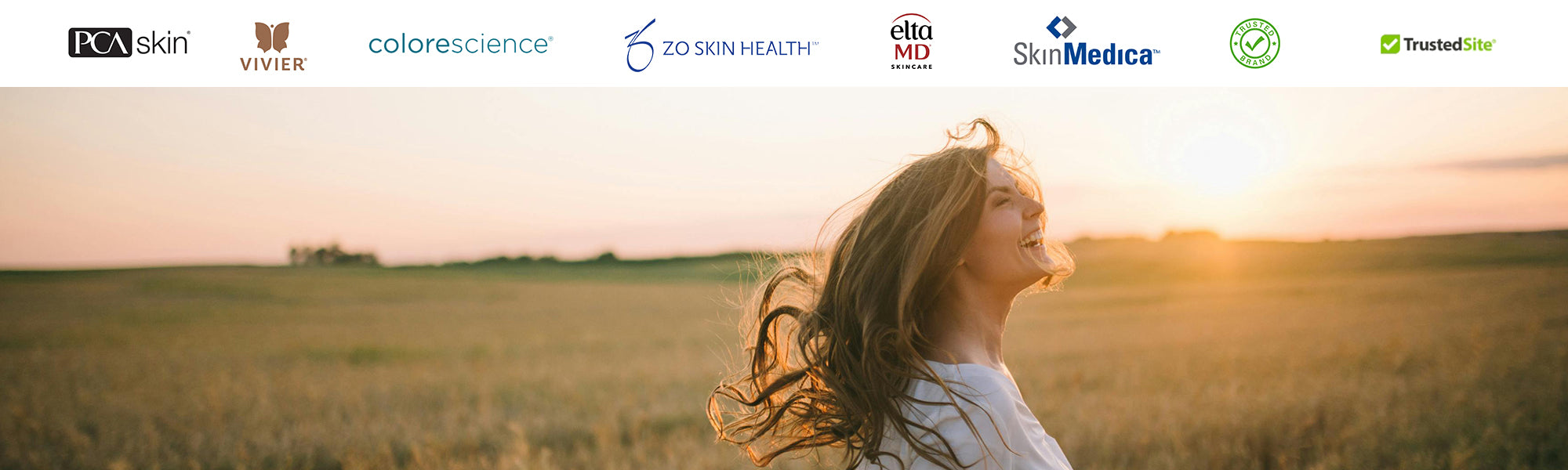 Woman smiling in golden field during sunset representing natural skincare glow with brands from Skin Boutique Online.